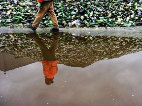 A worker at a glass recycling facility strolls past a mountain of bottles in the Netherlands in 2010.