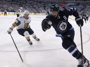 Winnipeg Jets centre Mark Scheifele (right) tries to spin away from the checking of Vegas Golden Knights defenceman Nate Schmidt during Game 1 of their Western Conference final series in Winnipeg on Saturday, May 12, 2018.