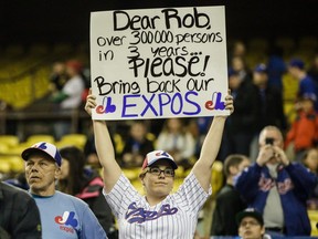 A baseball fan holds a sign asking MLB commissioner Rob Manfried to bring back the Montreal Expos before the second exhibition game between the Toronto Blue Jays and the Boston Red Sox at the Olympic Stadium in Montreal on Saturday, April 2, 2016.