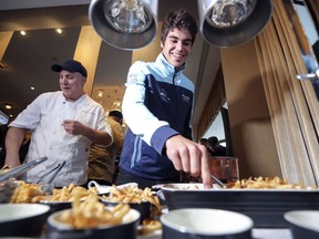 Williams F1 driver Lance Stroll makes poutine during promotional event sponsored by data protection company Acronis in Montreal Tuesday June 5, 2018. Ristorante Beatrice chef Shant Manquelian supervises the competition at left.