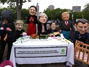 Members of OXFAM dressed as the "G7 leaders" pose for pictures outside the Quebec provincial building ahead of the G7 summit in Quebec City, Quebec.