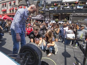 Canadian Paralympic swimmer Benoit Huot left, and Olympic diver Roseline Filion right get instructions on how to change a F1 tire before competing during Grand Prix festivities on Crescent street in Montreal, on Thursday, June 7, 2018.