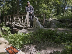 Seiji Gutierrez walks his dog along a path in Hudson on Sunday. The path crosses a footbridge that has stirred controversy over whether it's private land or town property.