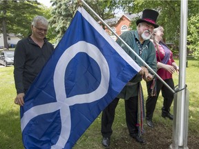 Archie Martin, who is a Métis storyteller from Rigaud, attaches a Métis flag that was raised during a ceremony in Hudson on Saturday.