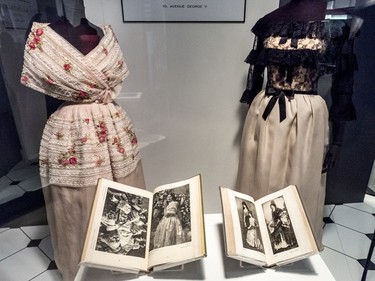 A dress, left, that draws on the regional costume of Valencia, as depicted in a book in the vitrine. The dress on the right draws on the lace mantilla worn by Spanish women, as illustrated in the 1926 book The Regional Costumes of Spain.