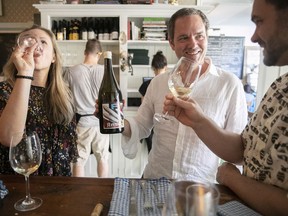 Montreal winemaker John Bambara, centre, holds a bottle of his wine, Fck Trmp, with sommeliers Vanya Filipovic and James Simpkins on June 21, 2018.
