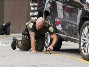 A Surete du Quebec crime scene investigator inspects the pavement next to a vehicle at the scene of the shooting death Steve Ovadia, a Laval man with ties to the Montreal Mafia.