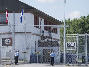 Guards stand outside the gates of an immigrant holding centre in Laval in this file photo.