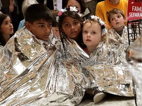 Children wrap themselves up with Mylar blankets to 'symbolically represent the thousands of children separated from families on the border, sleeping on floors and held in cages', during a protest at the rotunda of Russell Senate Office Building on June 21, 2018 on Capitol Hill in Washington, DC.