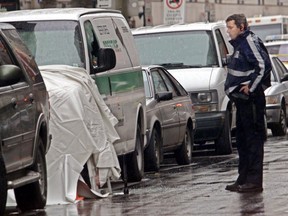 A police officer examines a spot on Cathcart St. where fellow officer Andre Leclerc was shot on July 12, 2001. Michael Sarandou was convicted of attempted murder.