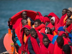Migrants keep warm in Red Cross blankets after arriving aboard a coast guard boat at Malaga's harbour on June 9, 2018, after an inflatable boat carrying 67 men, 1 women and 1 child was rescued by the Spanish coast guard off the Spanish coast.