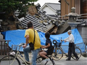 People pause to look at a collapsed house following an earthquake in Ibaraki City, north of Osaka prefecture on June 18, 2018.