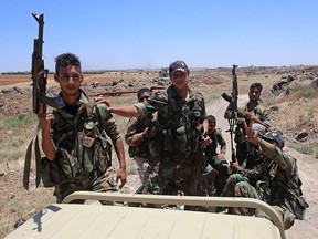 Syrian government forces' soldiers hold their weapons at the back of a pick-up truck during a government guided tour in the village of al-Sourah, province of Daraa, on June 29, 2018.