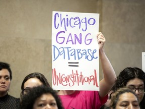People holds signs during a protest announcing a federal class-action lawsuit filed against the city by several community groups, alleging that officers, given "unlimited" discretion to add individuals to the department's massive gang database, often falsely label people as gang members "based solely on their race and neighborhood," Tuesday, June 19, 2018, at City Hall in Chicago. Four men who say they have been inaccurately labeled gang members by Chicago police were joined by members of various community groups at the protest.