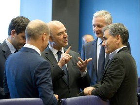 Greek Finance Minister Euclid Tsakalotos, right, speaks with European Commissioner for Economic and Financial Affairs Pierre Moscovici, second left, during a meeting of eurogroup finance ministers at EU headquarters in Luxembourg on Thursday, June 21, 2018. Eurozone nations are working on the final elements of a plan to get Greece successfully out of its eight-year bailout program and keep its massive debt burden manageable. At left is German Finance Minister Olaf Scholz, and at second right is French Finance Minister Bruno Le Maire.