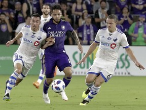 Orlando City's Josue Colman, center, tries to get possession of the ball between Montreal Impact's Daniel Lovitz, left, and Samuel Piette (6) during the first half of an MLS soccer match, Saturday, June 23, 2018, in Orlando, Fla.