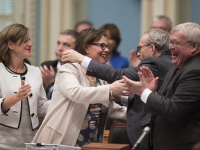 Lucie Charlebois, centre, is congratulated by Martin Coiteux, right, and others after the Quebec National Assembly adopted cannabis legislation on Tuesday, June 12, 2018.