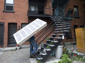Jim Hendry carries a boxspring up a set of stairs on what has become known as "Moving Day," in Montreal.