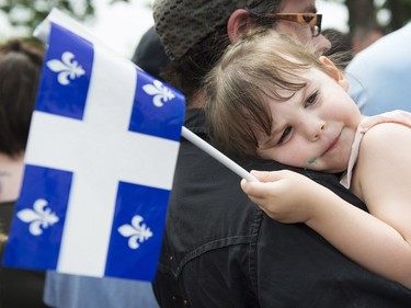 A young girl holds a Quebec flag during a Fête nationale celebration in a town west of Montreal, Sunday, June 24, 2018.