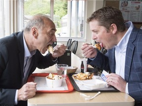 Conservative Leader Andrew Scheer, right, and Saguenay-Le Fjord candidate Richard Martel take a eat poutine at the famous Boivin cheese counter, Thursday, June 14, 2018 in Saguenay Que.