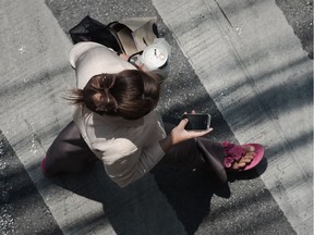 A woman looking at her smartphone while walking on a street in Bangkok.