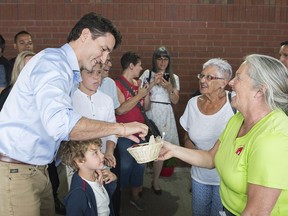 Prime Minister Justin Trudeau takes a stawberry from a vendor during a visit to a market in Drummondville, Que., Saturday, June 23, 2018.