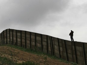FILE - This April 27, 2006 file photo shows the U.S.-Mexico border fence near Smuggler's Gulch west of the San Ysidro Port of Entry in San Diego. Twenty-six days after being apprehended on May 23, 2018 at the U.S.-Mexico border with his son, a Brazilian man in detention says he has no idea when he may see his 9-year-old, who he fears is distraught and having difficulty communicating since he only speaks Portuguese.