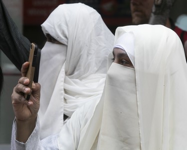 Women wearing niqabs watch the Canada Day parade in Montreal on Sunday July 1, 2018. (Pierre Obendrauf / MONTREAL GAZETTE)