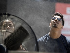 Xavier Selly cools down in front of a large fan that is equipped with a water misting ring at the Montreal International Jazz Festival July 3, 2018.