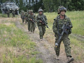 Canadian soldiers from India Company, enhanced Forward Presence Battle Group Latvia, move toward the woods during Exercise SABER STRIKE 2018, near Skrunda, Latvia on June 11, 2018.