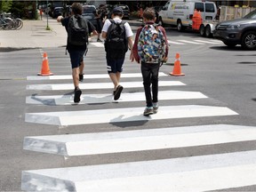 Three boys jump over freshly painted 3D crosswalk markings in the Outremont borough of Montreal on Tuesday, July 10, 2018.