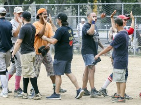 Players exchange high-fives following exhibition softball game between local players and Expos Nation at Jeanne Mance Park in Montreal Saturday July 14, 2018.  The event was held in response to the Plateau Mont-Royal's decision to close the north softball field in the same park.  The local players defeated Expos Nation 12-7.