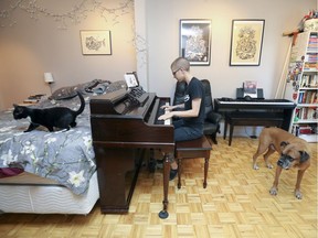While one of the two cats wanders off, boxer Charles Wallace listens as Raphaëlle Bigras Burrogano plays the piano in the double bed-and-living room in her St-Henri apartment. (John Mahoney / MONTREAL GAZETTE)