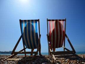 People relax in deck chairs on the beach in Brighton on July 18, 2014, as parts of the country were expected to experience the hottest day of the year so far and the Met Office issued a heatwave alert for southern England and the Midlands.  AFP PHOTO / CARL COURTCARL COURT/AFP/Getty Images ORG XMIT: 1888