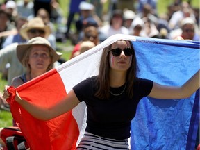 A soccer fan holds the French flag while watching the World Cup semi-final match against Belgium during a public watch party at Sue Bierman Park on July 10, 2018, in San Francisco, Calif.