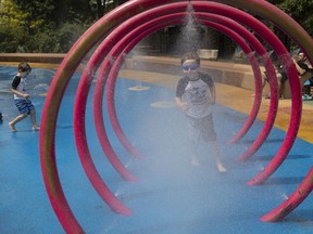 James Brittan, left, and his brother, Patrick Brittan runs through sprinklers at the Parc St-Michel splash pad in Montreal, on Friday, July 13, 2018. (Allen McInnis / MONTREAL GAZETTE) ORG XMIT: 61038