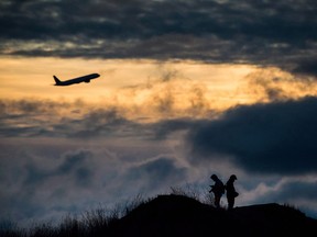 An Air Canada plane takes off as Andrew Yang, left, and Kevin Jiang take photographs of planes at Vancouver International Airport.