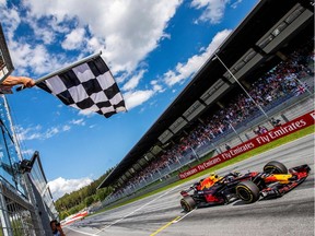 The flagman waves the chequered flag as Red Bull's Dutch driver Max Verstappen crosses the finish of the Austrian Formula One Grand Prix in Spielberg, central Austria, on July 1, 2018.