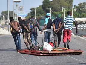 Looters carry away items in Delmas, a commune near Port-au-Prince, during protests against the rising price of fuel, on July 8, 2018, in Haiti.