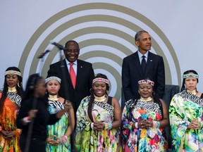 Former US President Barack Obama (R) and South African President Cyril Ramaphosa (L), stand on stage behind the Soweto Gospel Choir, during the 2018 Nelson Mandela Annual Lecture at the Wanderers cricket stadium in Johannesburg on July 17, 2018. Former US president Barack Obama will deliver the Nelson Mandela Annual Lecture, urging young people to fight to defend democracy, human rights and peace, to a crowd of 15,000 people at the club as the centrepiece of celebrations marking 100 years since Nelson Mandela's birth. Obama has made relatively few public appearances since leaving the White House in 2017, but he has often credited Mandela for being one of the great inspirations in his life.