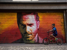 A boy bikes past a mural of British actor Andrew Lincoln as Rick Grimes in The Walking Dead.