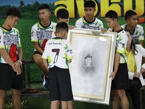 Coach Ekkapol Janthawong and the 12 boys show their respect and thanks as they hold a portrait of Saman Gunan, the retired Thai SEAL diver who died during their rescue attempt, during a press conference in Chiang Rai, northern Thailand, Wednesday, July 18, 2018.
