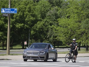 A police officer answers questions from a vehicle after it drives into the parking lot by the Belvedere Camillien-Houde on June 2, 2018. Many cars were directed off the mountain road.