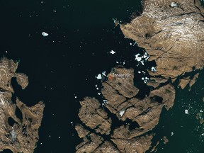 The satellite image, which was captured by Sentinel-2A on July 9, 2018, provided by European Space Agency esa on Tuesday, July 18, 2018 shows a huge iceberg perilously close to the village of Innaarsuit on the west coast of Greenland. If the berg breaks apart, waves resulting from the falling ice could wash away parts of the village. (esa via AP)