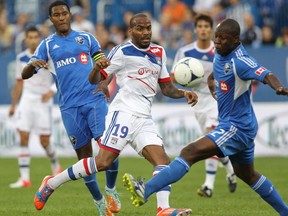 Jimmy Briand, centre, of Olympique Lyonnais of the French Ligue 1 fights for a ball with Nelson Rivas of the Montreal Impact of the MLS in an international friendly match at Saputo stadium in Montreal Tuesday, July 24, 2012. On the left is Patrice Bernier of the Impact.