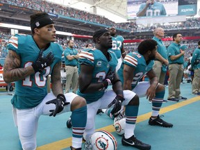 FILE - In this Sunday, Oct. 23, 2016, file photo, Miami Dolphins wide receiver Kenny Stills (10), free safety Michael Thomas (31) and defensive back Chris Culliver (29) kneel during the National Anthem before the first half of an NFL football game against the Buffalo Bills in Miami Gardens, Fla. Miami Dolphins players who protest on the field during the national anthem this season could be suspended for up to four games under a new team policy issued to players this week. The policy obtained by The Associated Press on Thursday, July 19, 2018 classifies anthem protests as conduct detrimental to the club, punishable by suspension without pay, a fine or both.