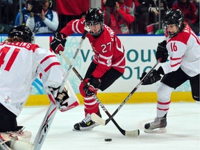 Canada's Gina Kingsbury, centre, fights for the puck with Switzerland's Christine Meier during preliminary-round game at the the XXI Winter Olympic Games in Vancouver on Feb. 15, 2010.