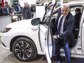 Philippe Couillard steps out of an electric car after driving into an electric car show April 20, 2018, in Montreal.