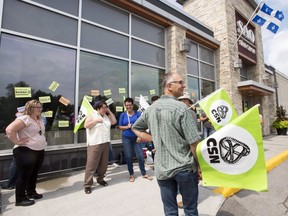 SAQ employees walk the picket line in front of an SAQ outlet on the first day of their strike to protest against lagging contract negotiations, Tuesday, July 17, 2018 in Rosemère.