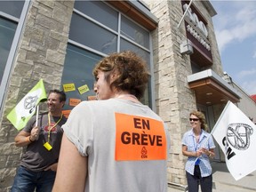 SAQ employees walk the picket line in front of an outlet on the first day of their strike to press lagging contract negotiations, July 17, 2018.